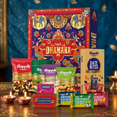Burgundy and gold Happilo gift box beside brass bowls of almonds, cashews, pistachios and green raisins, shown as a dry fruits gift box for clients